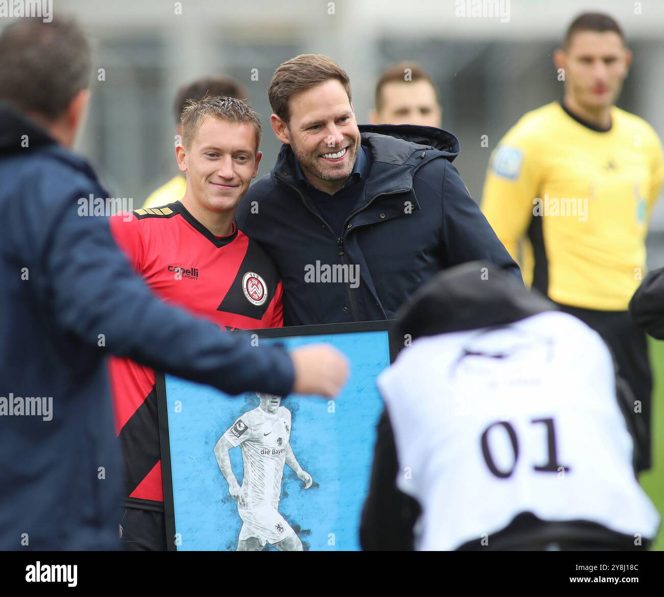 München, Deutschland, 05. Oktober 2024: Fussball, Herren, 3.Liga, Saison 2024/2025, TSV 1860 München - SV Wehen Wiesbaden, Grünwalder Stadion Fabian Greilinger (SV Wehen Wiesbaden) (li.) Wird von Dr Christian Werner, Geschäftsführer Sport (TSV 1860 München) (rientro) vor dem Spiel offiziell verabschiedet, mit einem Bild DFB regolamenti vietano qualsiasi uso di fotografie come sequenze di immagini e/o quasi-video Foto Stock