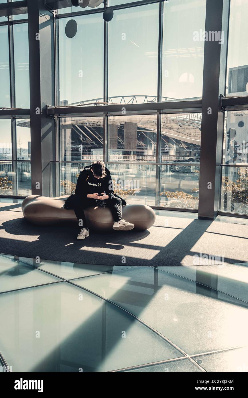 Uomo seduto di fronte alla vista dell'Estadio do Dragao sul suo telefono a Porto, in Portogallo Foto Stock