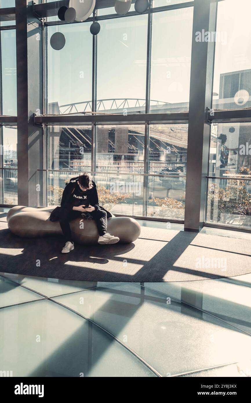 Uomo seduto al telefono nella finestra del centro commerciale, vista dell'Estadio do Dragao, Porto Foto Stock