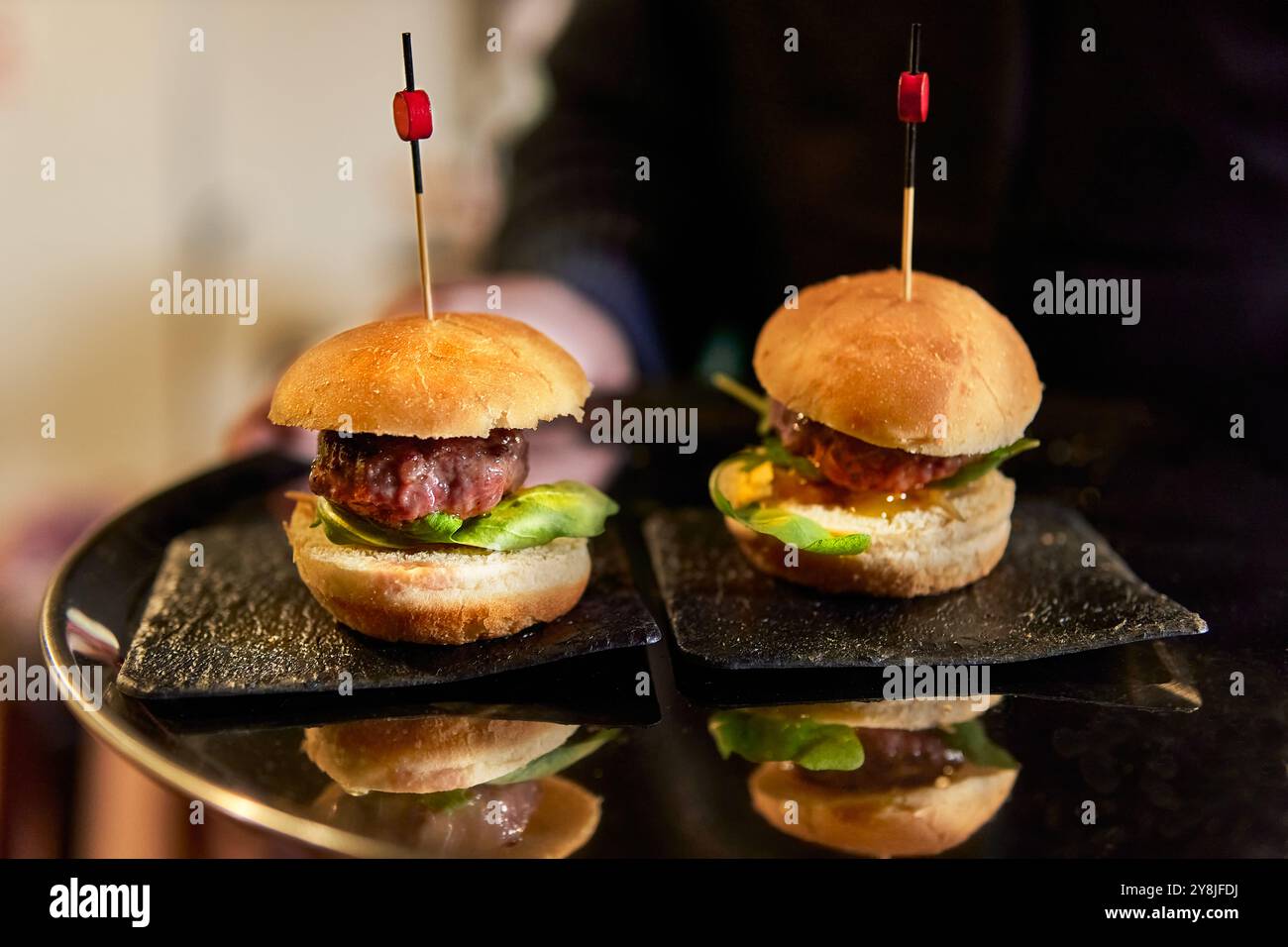 Il cameriere offre hamburger e stuzzichini su un vassoio presso un laboratorio di catering Foto Stock