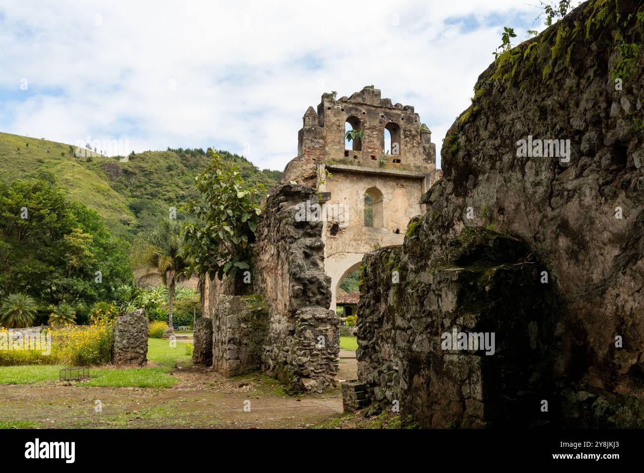 Immagine dei resti di una chiesa di epoca coloniale a Ujarras, Cartago, Costa Rica. La struttura è circondata dal verde e dai fiori, con un percorso pulito Foto Stock