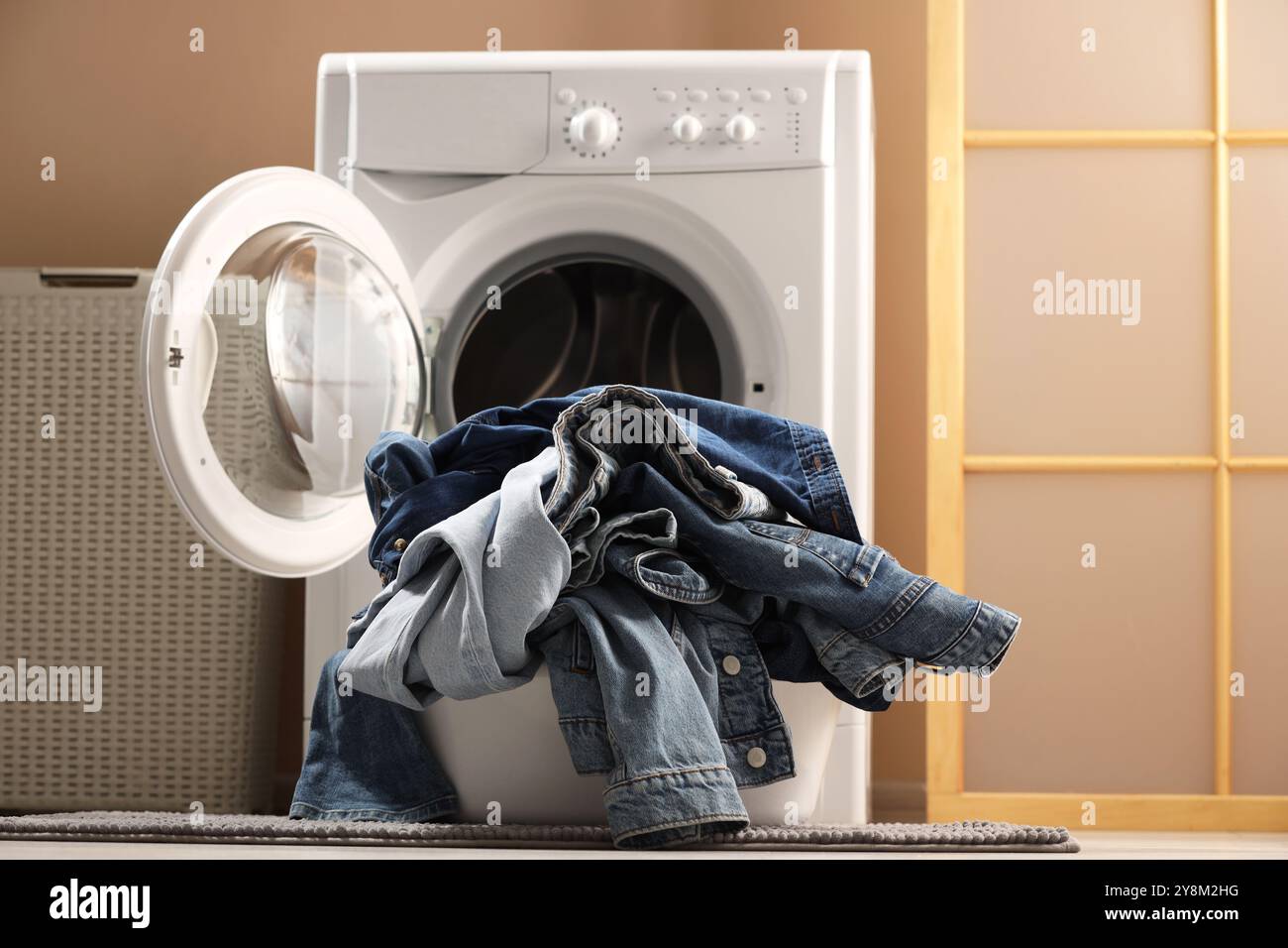 Lavatrice con jeans sporchi e altri indumenti in denim all'interno Foto Stock