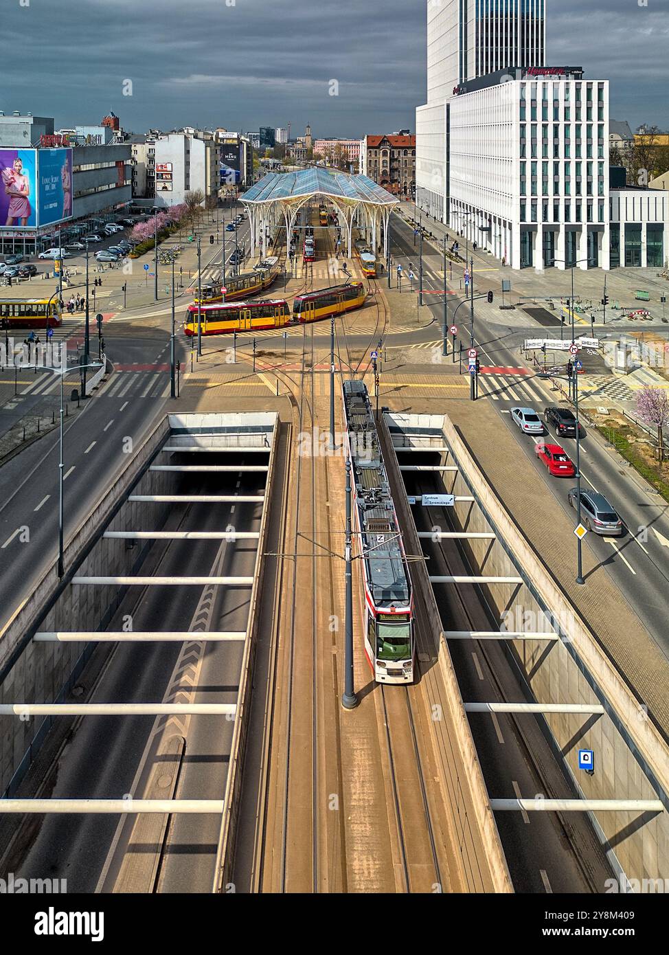 Titolo: Veduta aerea di una moderna stazione del tram a Łódź, Polonia, con tram multipli, baldacchino di vetro e infrastrutture urbane nel cuore della città Foto Stock