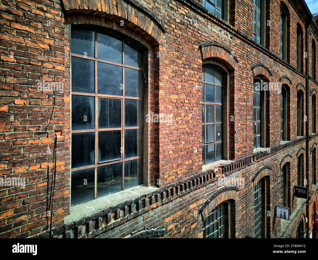 Edificio industriale in mattoni con scala in metallo e finestre d'epoca a Łódź, che cattura il patrimonio architettonico urbano e la rivitalizzazione artistica Foto Stock