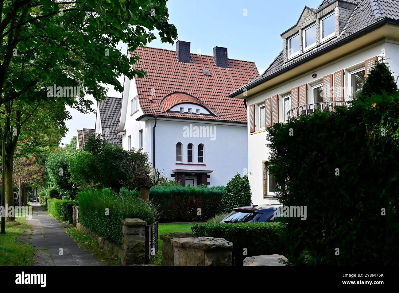 15.09.2024, Deutschland, Nordrhein-Westfalen, Ruhrgebiet, Dortmund. Siedlung Gartenstadt. Die Dortmunder Gartenstadt ist ein beliebtes urbanes Wohnquartier. Die Siedlung wurde ab dem Jahr 1913 nach einem von Stadtrat Cremer entwickelten Stadtplan als Villenkolonie verwirklicht. DAS Sielungskonzept stammt vom Architekten Heinrich Metzendorf. Heute leben ca. 10,000 Menschen in der Siedlung. Blick in eine Wohnstrasse mit Wohnhaeusern in der Siedlung. Siedlung Gartenstadt a Dortmund *** 15 09 2024, Germania, Renania settentrionale-Vestfalia, regione della Ruhr, tenuta di Dortmund Gartenstadt Dortmund Gartenstadt es Foto Stock