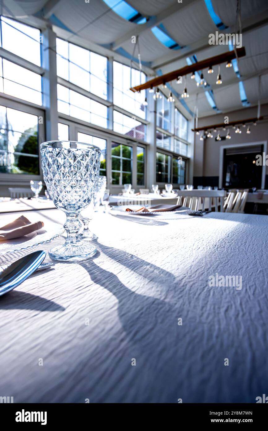 Vetro di cristallo sul tavolo in una luminosa sala banchetti con pareti in vetro. Foto scattate durante il giorno, con la luce del sole che scorre. Foto Stock