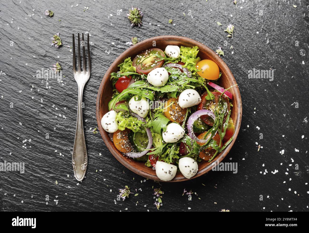 Lay piatto di insalata di verdure con mozzarella, lattuga, pomodori ciliegini, rafano, cetriolo, cipolla e basilico nel piatto di argilla Foto Stock