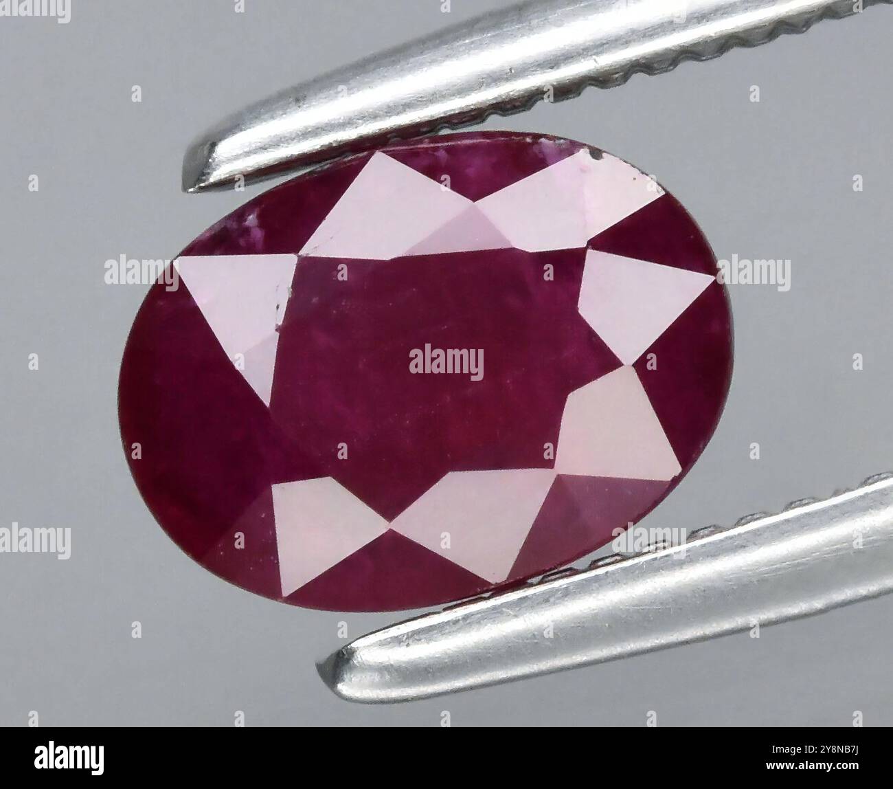 Rubino gemma naturale con taglio ovale che sfoggia tonalità rosso intenso e brillantezza sfaccettata. Foto Stock