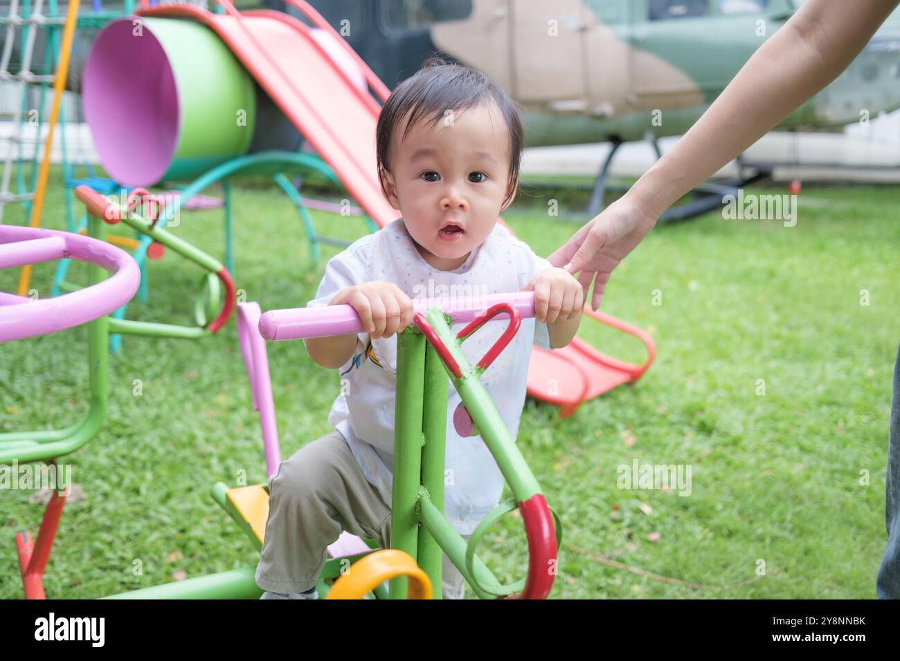 Allegro bambino asiatico che si diverte sull'erba al parco giochi Foto Stock