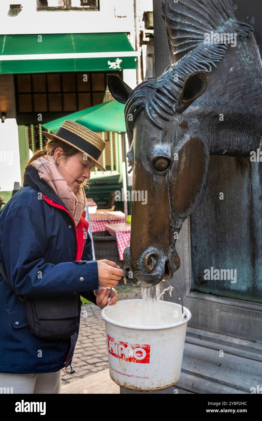 Belgio, Fiandre, Bruges, Wijngaardstraat, autista di carrozza che riempie il secchio presso la fontana della testa di cavallo Foto Stock