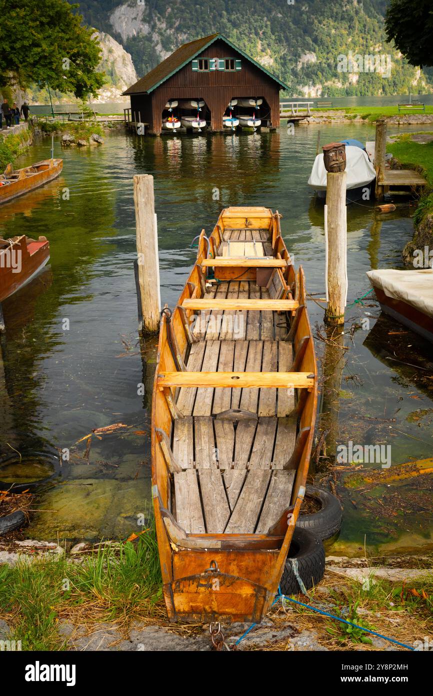 Barca in legno annessa con lago, garage per barche e montagna soleggiata sullo sfondo Foto Stock