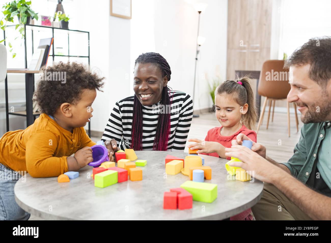 Famiglia multirazziale impegnata nel gioco con blocchi colorati all'interno Foto Stock