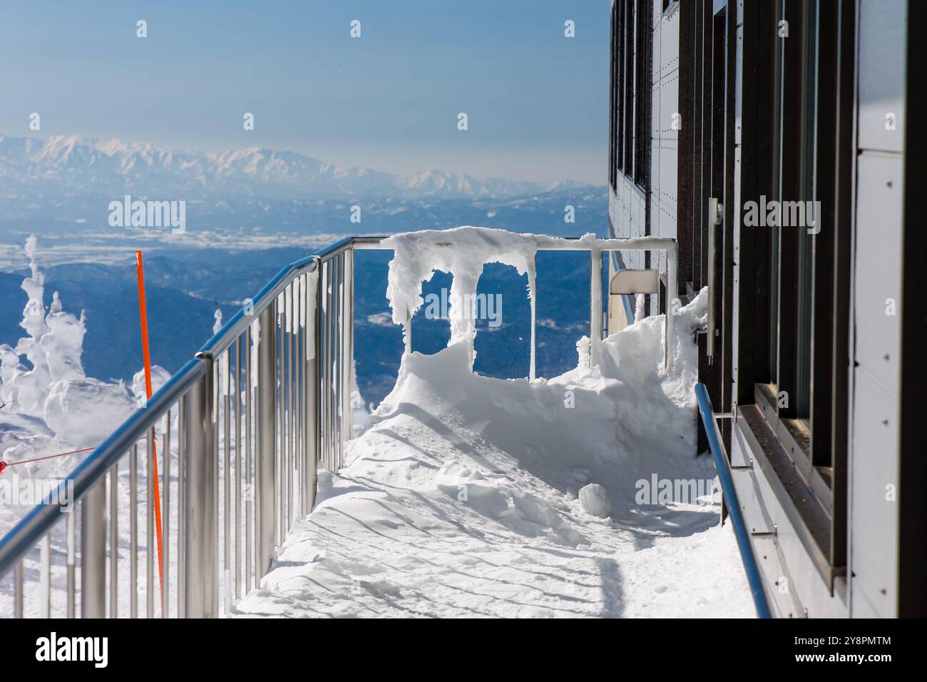 Recinzione incrostata di neve e ghiaccio che si affaccia sul paesaggio alpino Foto Stock