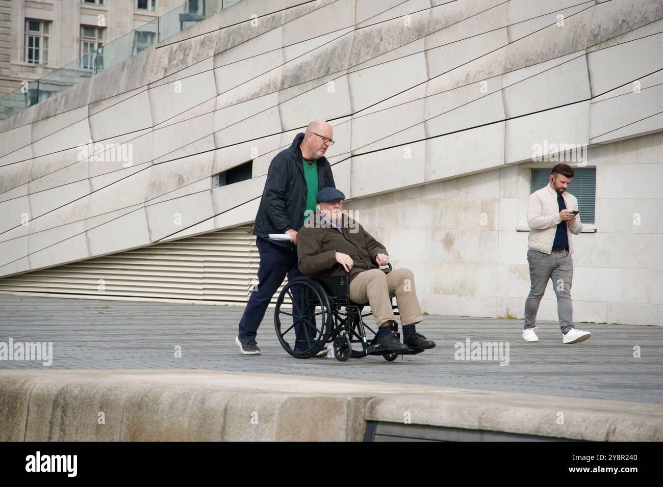 Vecchio che viene spinto su una sedia a rotelle Foto Stock