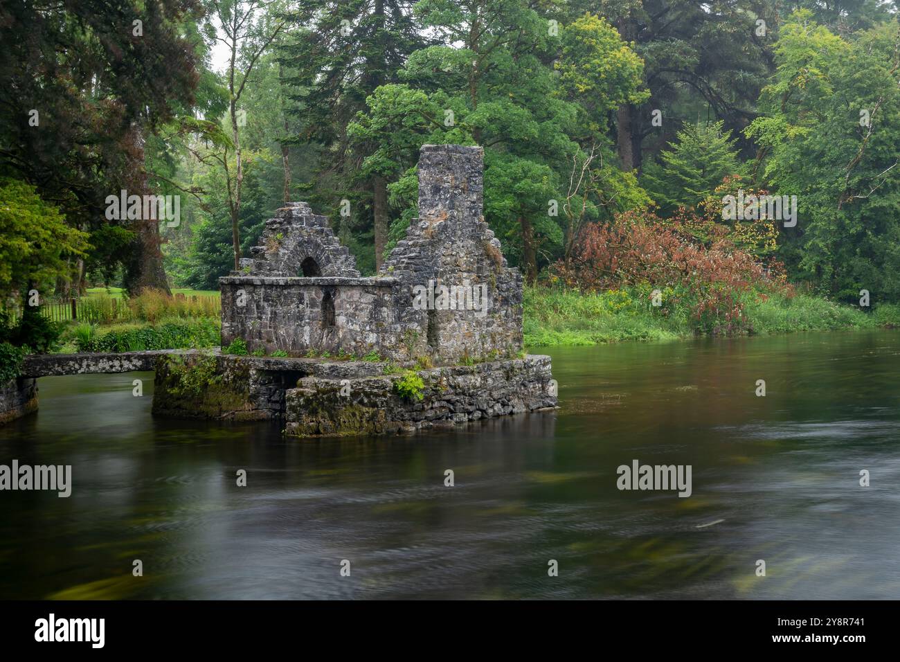 Incantevole casa di pescatori di pietra Monk sul fiume Cong a Cong Abbey, in Irlanda, in una giornata di pioggia Foto Stock