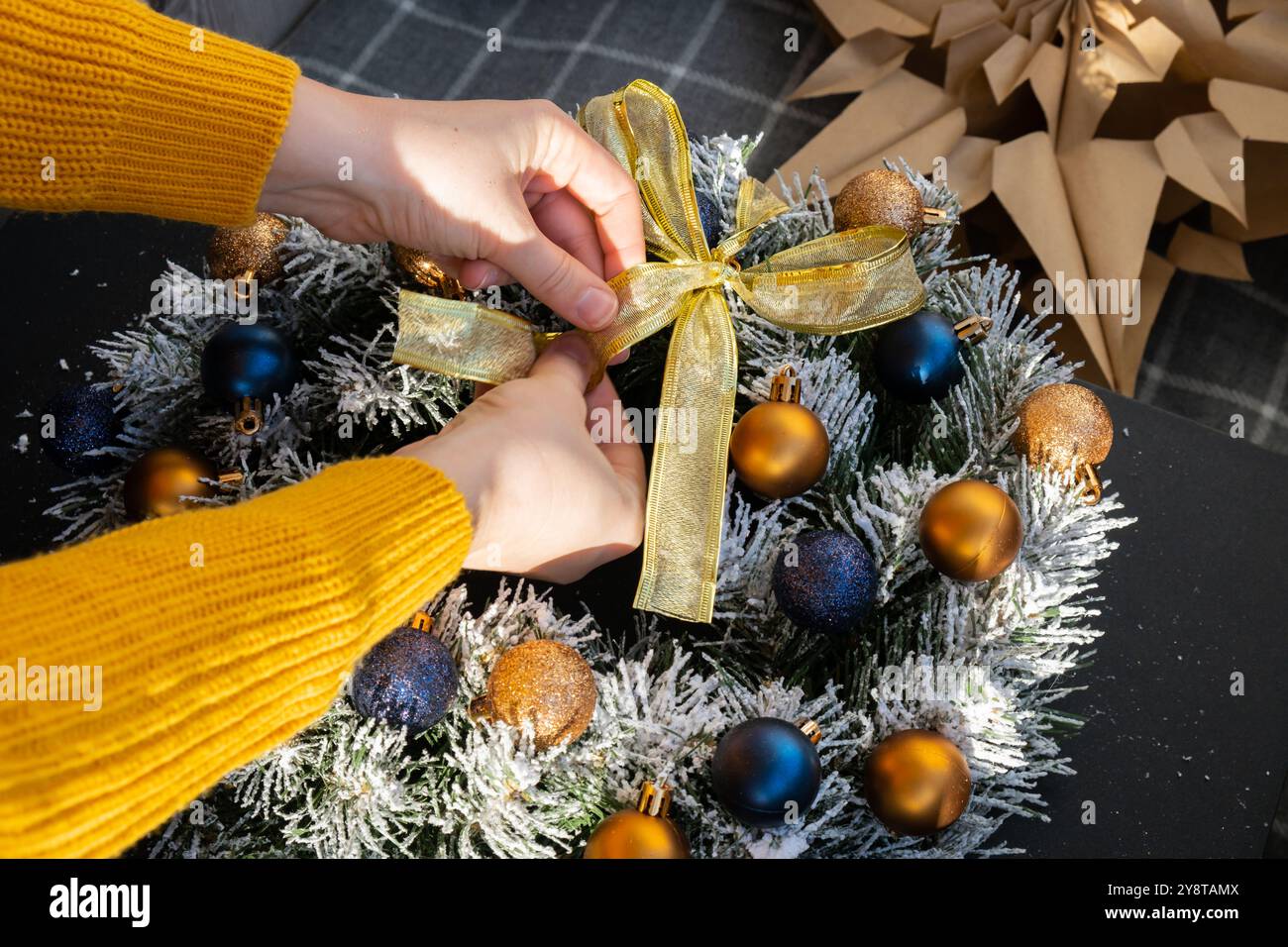 Donna che lega il nastro decorativo fai da te processo di donna che crea la disposizione natalizia con decorazioni di colori blu e giallo. Piccola impresa, imprenditore autonomo, carriera autonoma. Serie di istruzioni artigianali. Decorazioni ecologiche per le vacanze invernali a zero sprechi. Anno nuovo Foto Stock