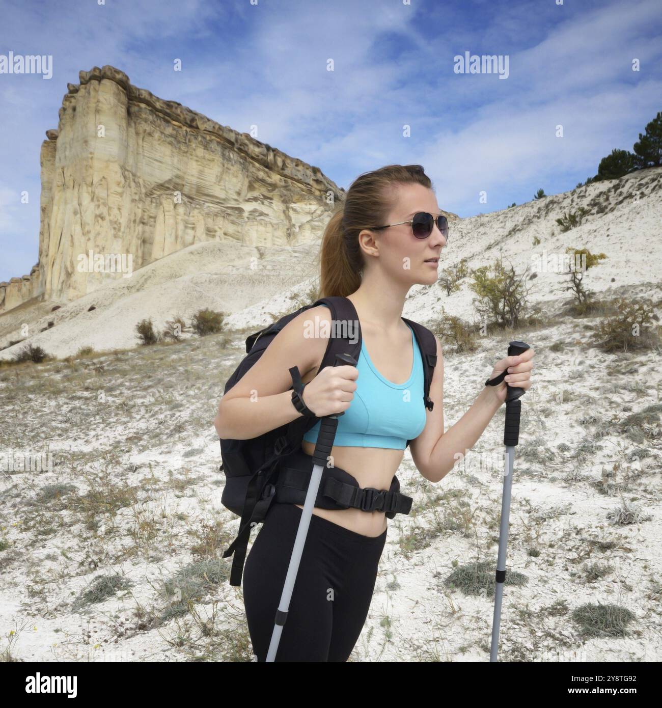 Giovane donna con zaino e bastoncini da trekking in montagna Foto Stock