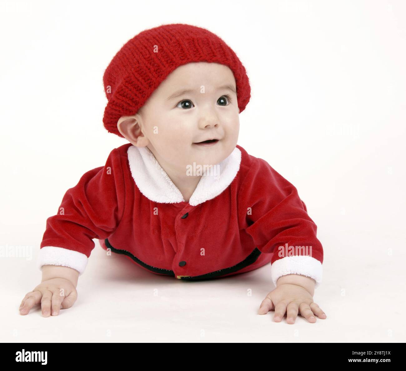 Carino Infant Boy in una composizione orizzontale strisciando nel vestito rosso e hat Foto Stock