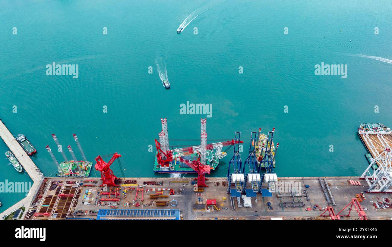 QINGDAO, CINA - 6 OTTOBRE 2024 - Un rimorchiatore ad alta potenza tira la piattaforma di costruzione di energia eolica offshore di quarta generazione "Ganghangping 5" di Foto Stock