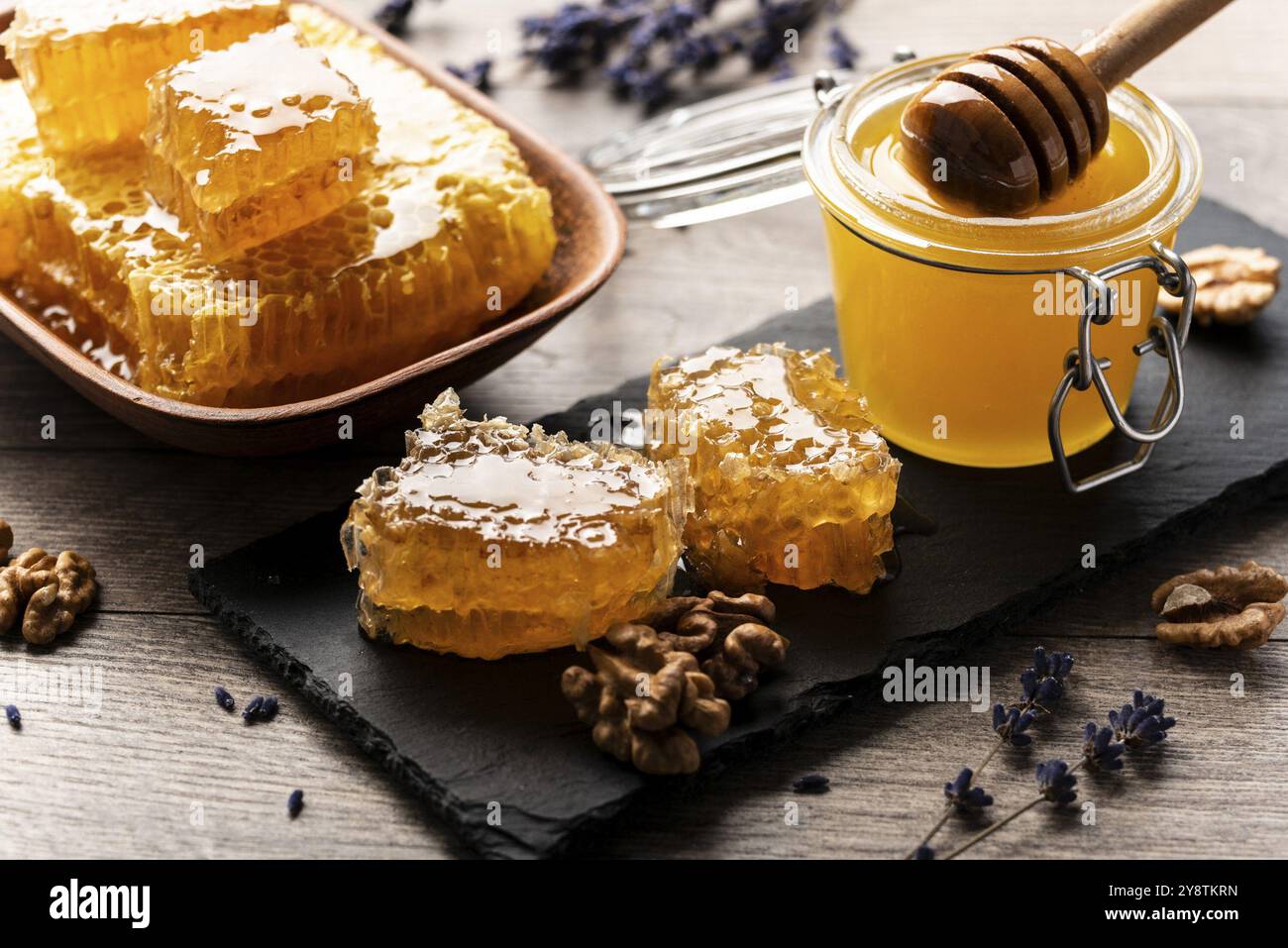 Nido d'ape su vassoio di ardesia con miele e noci sul tavolo da cucina Foto Stock