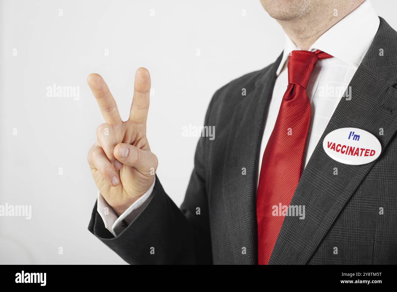 Uomo caucasico di mezza età in tuta con spillo sono vaccinato mostrando un gesto V. Foto Stock