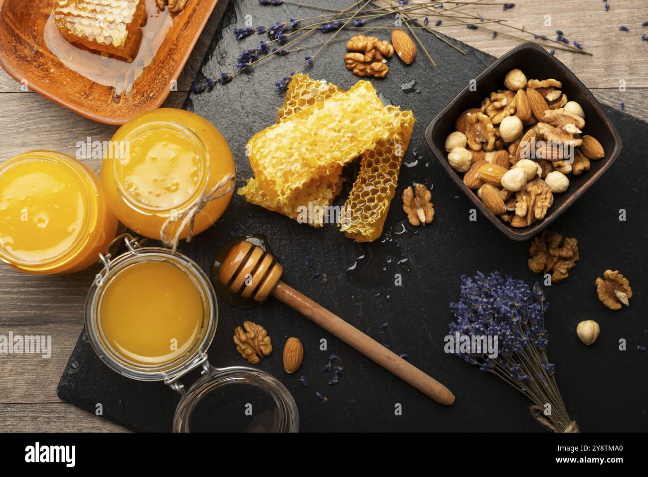 Nido d'ape su vassoio di ardesia con miele e noci sul tavolo da cucina Foto Stock