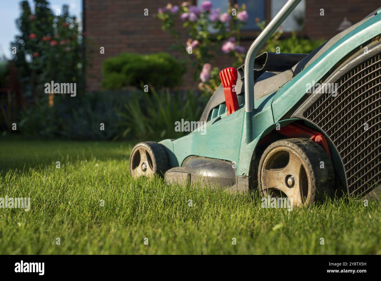 Prato mover su erba verde di fronte og casa di mattoni Foto Stock