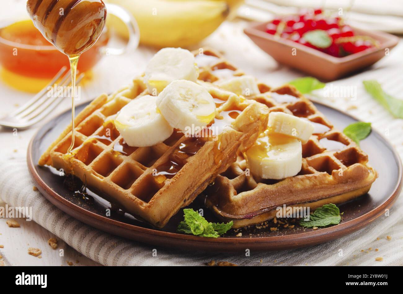 Waffle belgi croccanti fatti in casa serviti con banana e miele Foto Stock