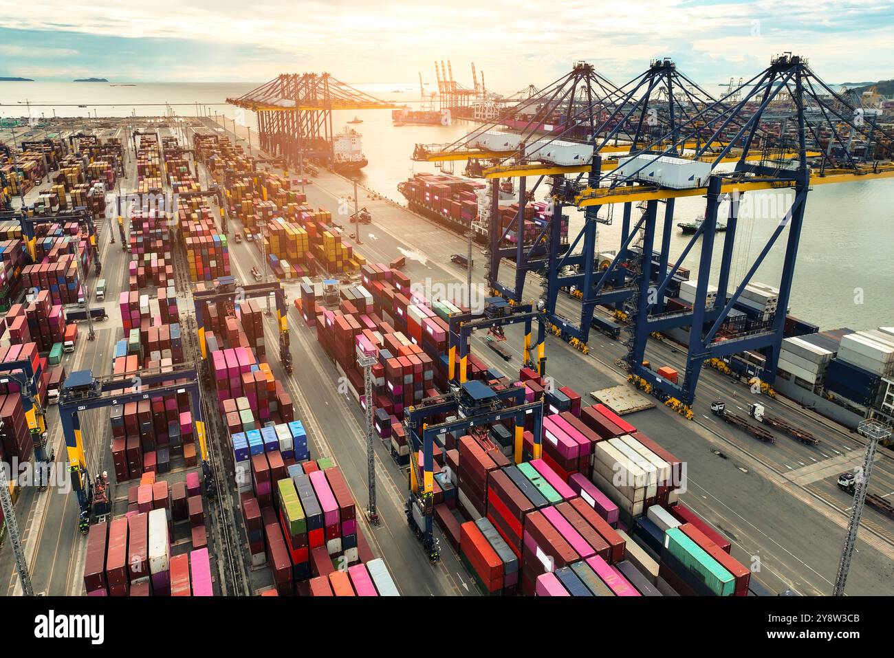 Nave portacontainer ancorata al porto con autocarri e gru. Hub logistico globale. Operazioni di trasporto marittimo di merci. Commercio internazionale e catena di approvvigionamento Foto Stock