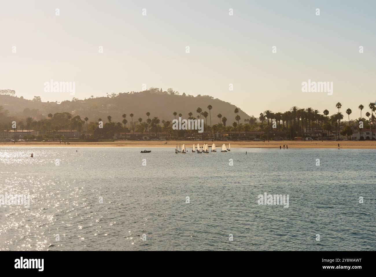 Una vasta distesa d'acqua caratterizzata da una pittoresca spiaggia lungo alte montagne che si innalzano magnificamente sullo sfondo Foto Stock