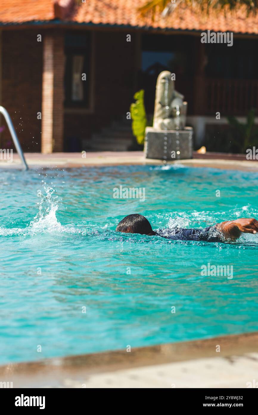 Uomo che nuota in stile libero nella scintillante piscina. Vivace piscina estiva con acque blu cristalline. Foto Stock