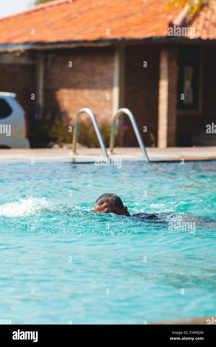 Uomo atletico in azione nuotare sotto il sole. Acque fresche e sole brillante. Foto Stock