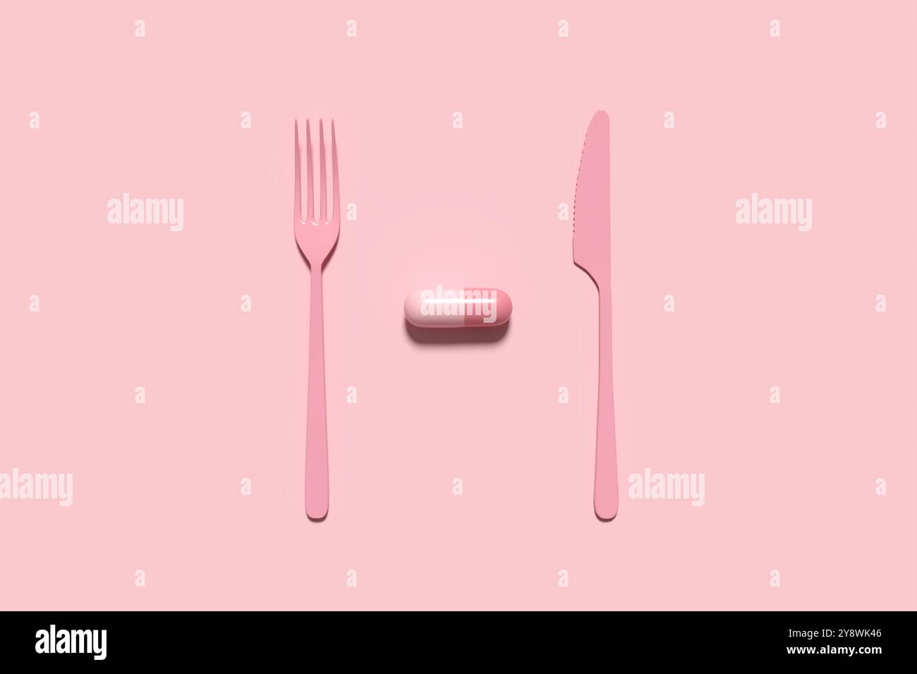 Pillola medica o capsula servita con una forchetta e un coltello su sfondo rosa. Prescrizione abuso di droga, dipendenza e disturbo da uso di sostanze. Supplementi alimentari Foto Stock
