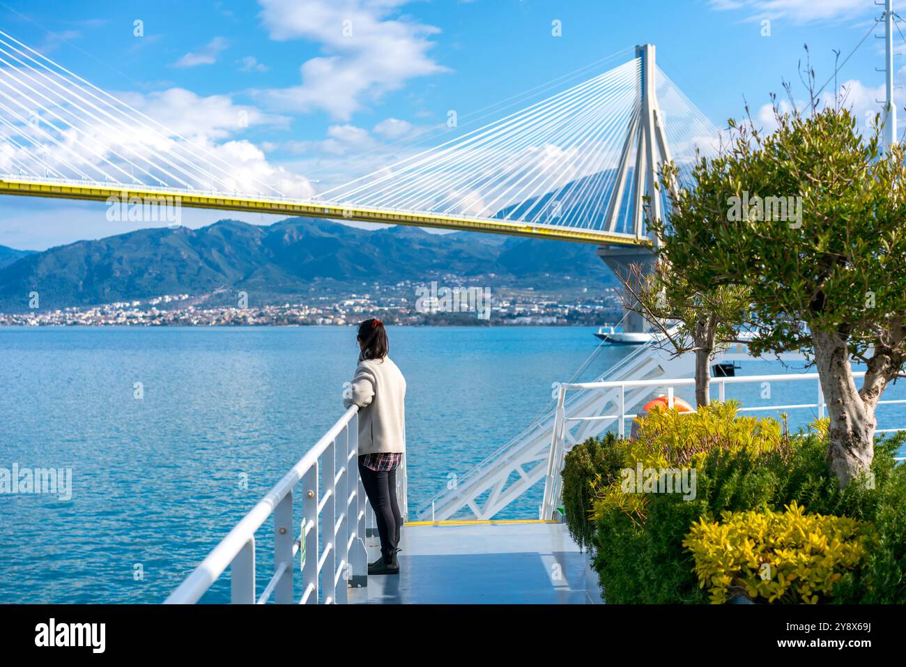 Donna su un traghetto che guarda il ponte Charilaos Trikoupis in Grecia Foto Stock