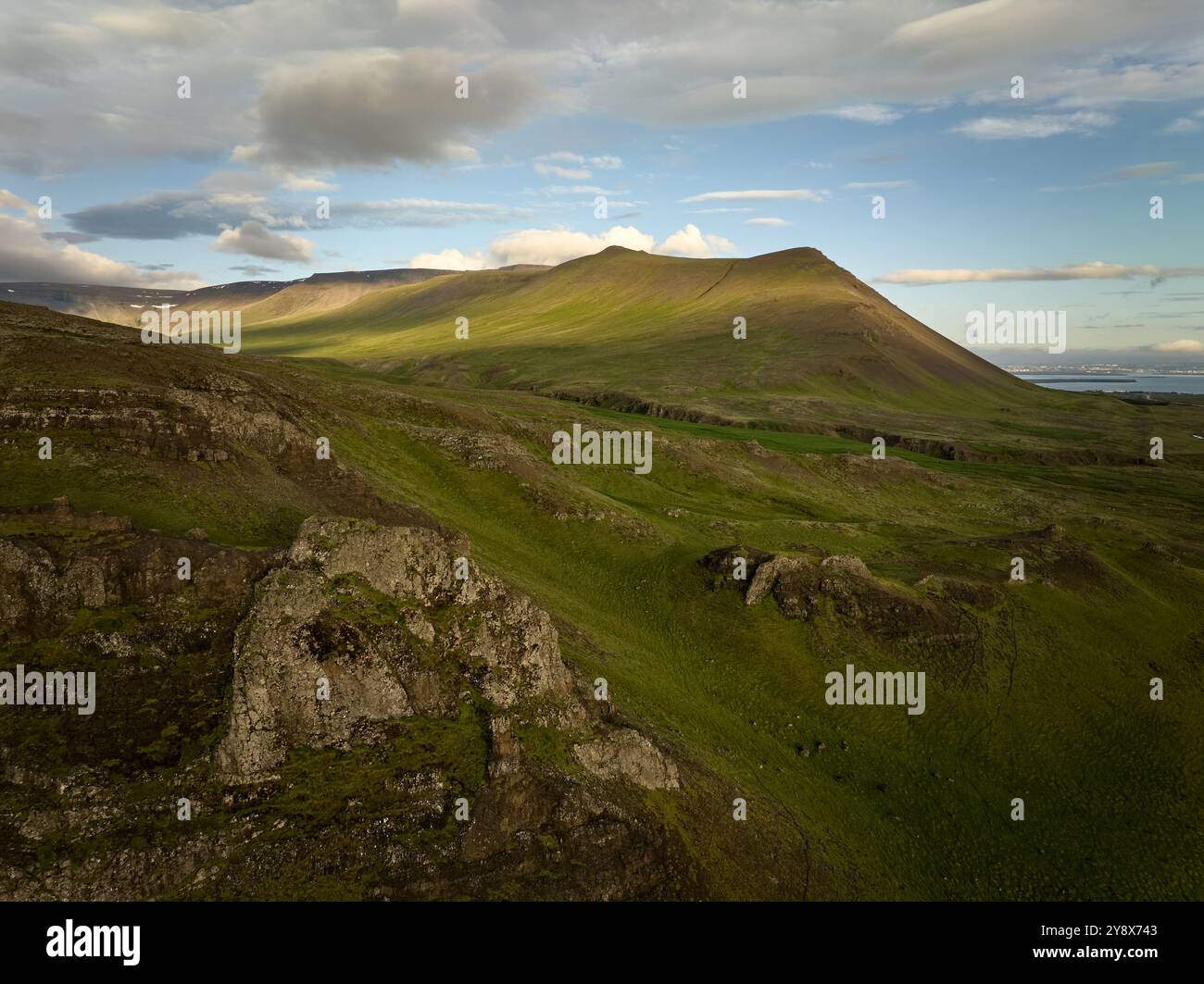 Paesaggio montuoso ricoperto di erba verde sotto il cielo blu nuvoloso Foto Stock