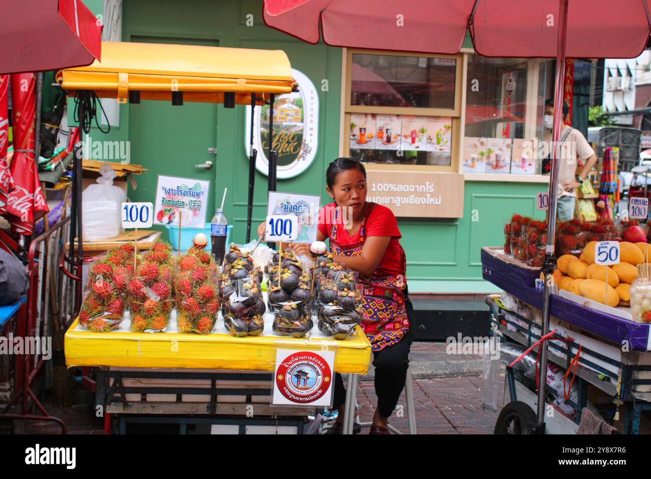 Bangkok. Una donna che vende frutta (rambutan e mangostano) per le strade di Chinatown. Il quartiere cinese della capitale thailandese è tra i più grandi al mondo. Foto Stock