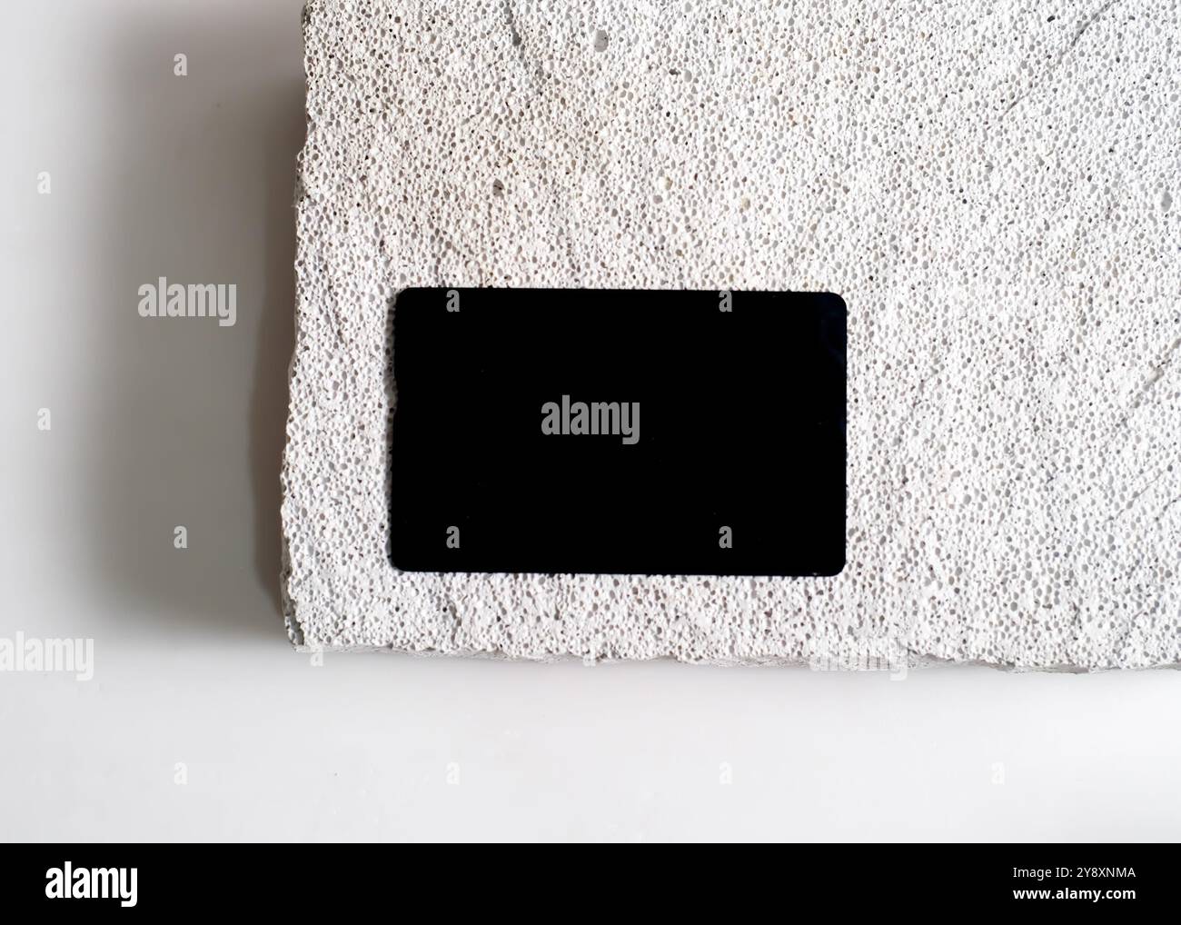 Un sofisticato mockup di carte nere elegantemente visualizzato su un pulito sfondo in pietra bianca. Questo design minimalista mette in risalto l'eleganza e le vers Foto Stock