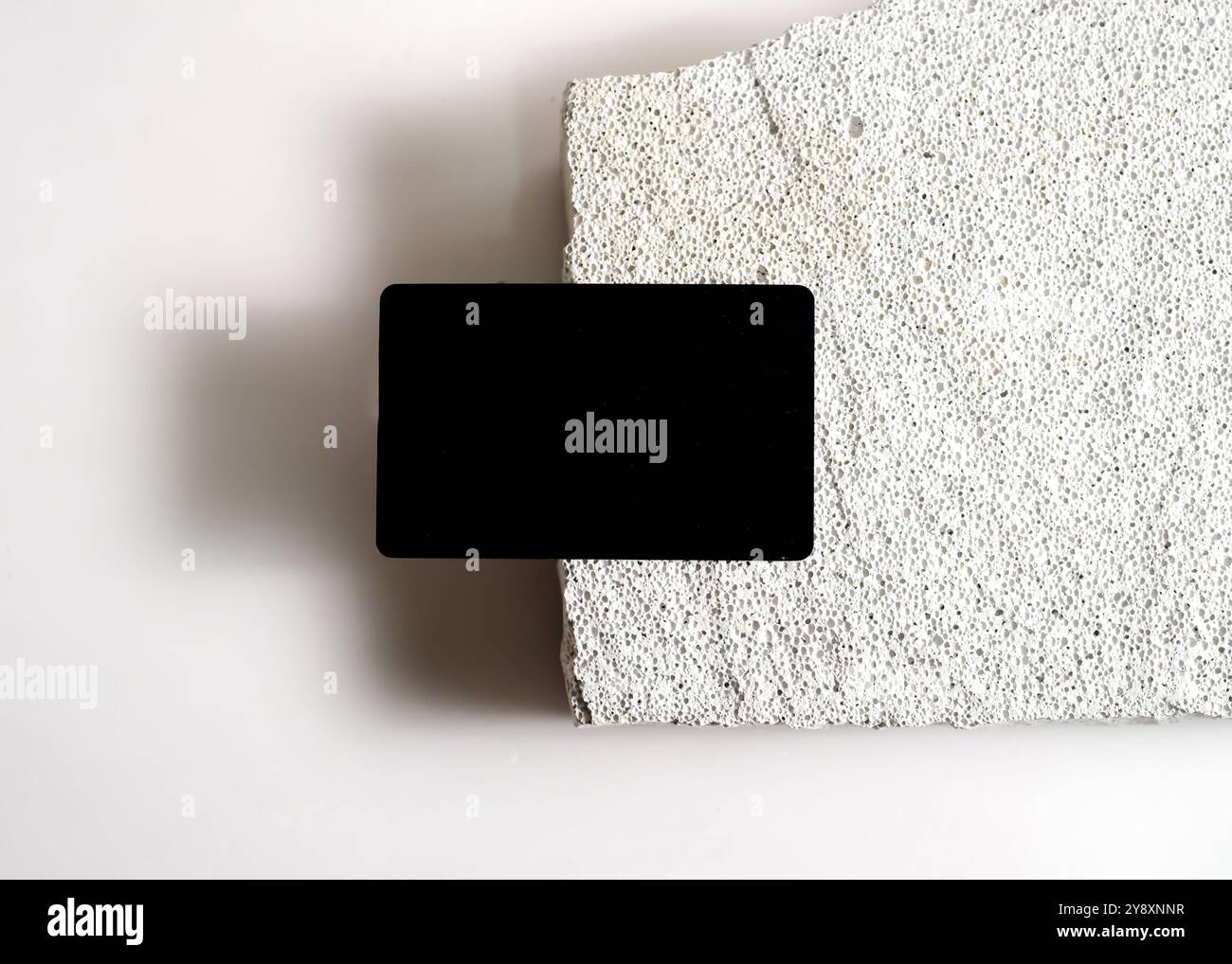 Un sofisticato mockup di carte nere elegantemente visualizzato su un pulito sfondo in pietra bianca. Questo design minimalista mette in risalto l'eleganza e le vers Foto Stock