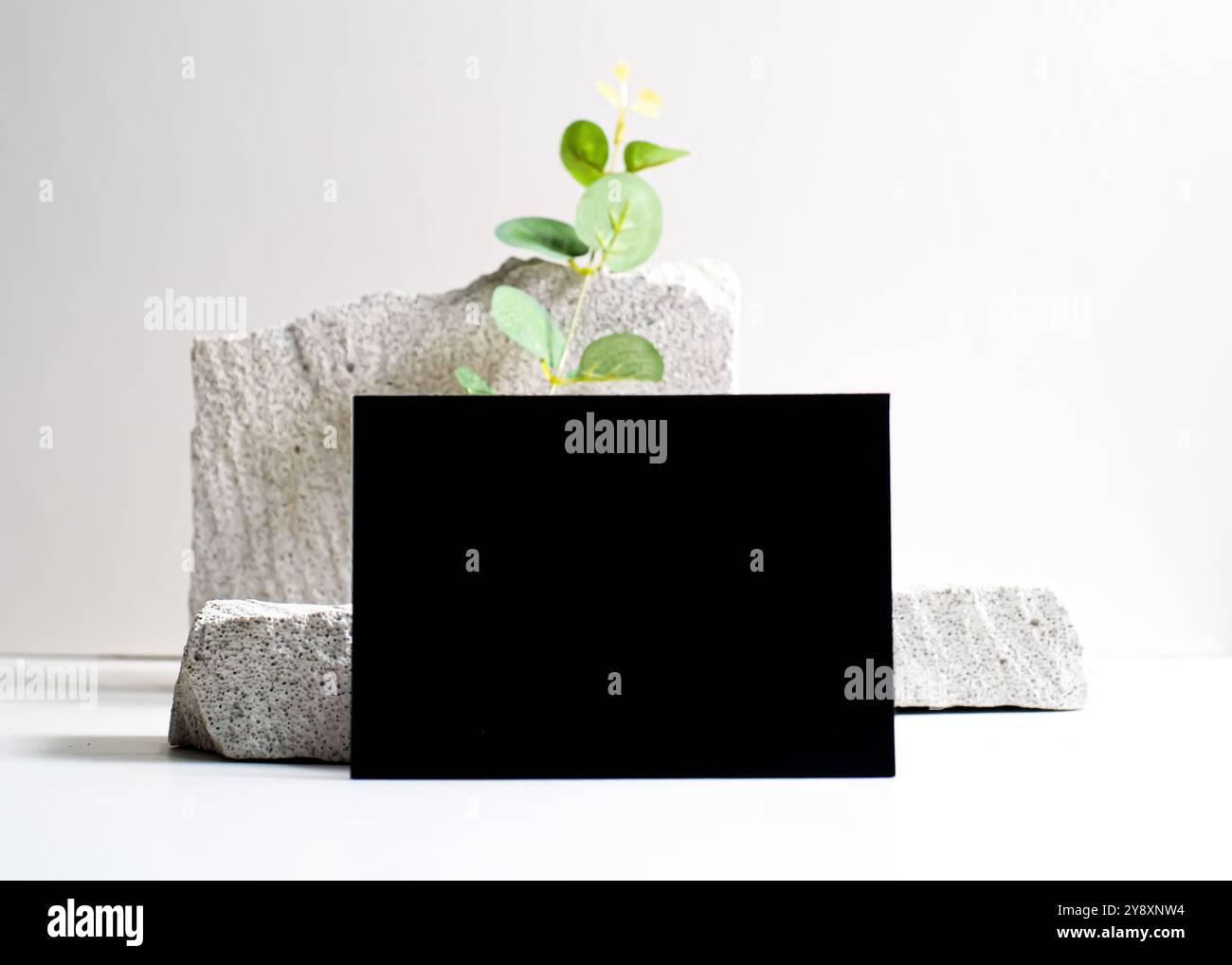 Un sofisticato mockup di carte nere elegantemente visualizzato su un pulito sfondo in pietra bianca. Questo design minimalista mette in risalto l'eleganza e le vers Foto Stock