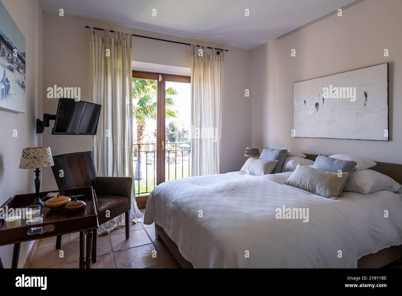 Letto matrimoniale con poltrona e TV a parete nella villa spagnola di Maiorca. Foto Stock