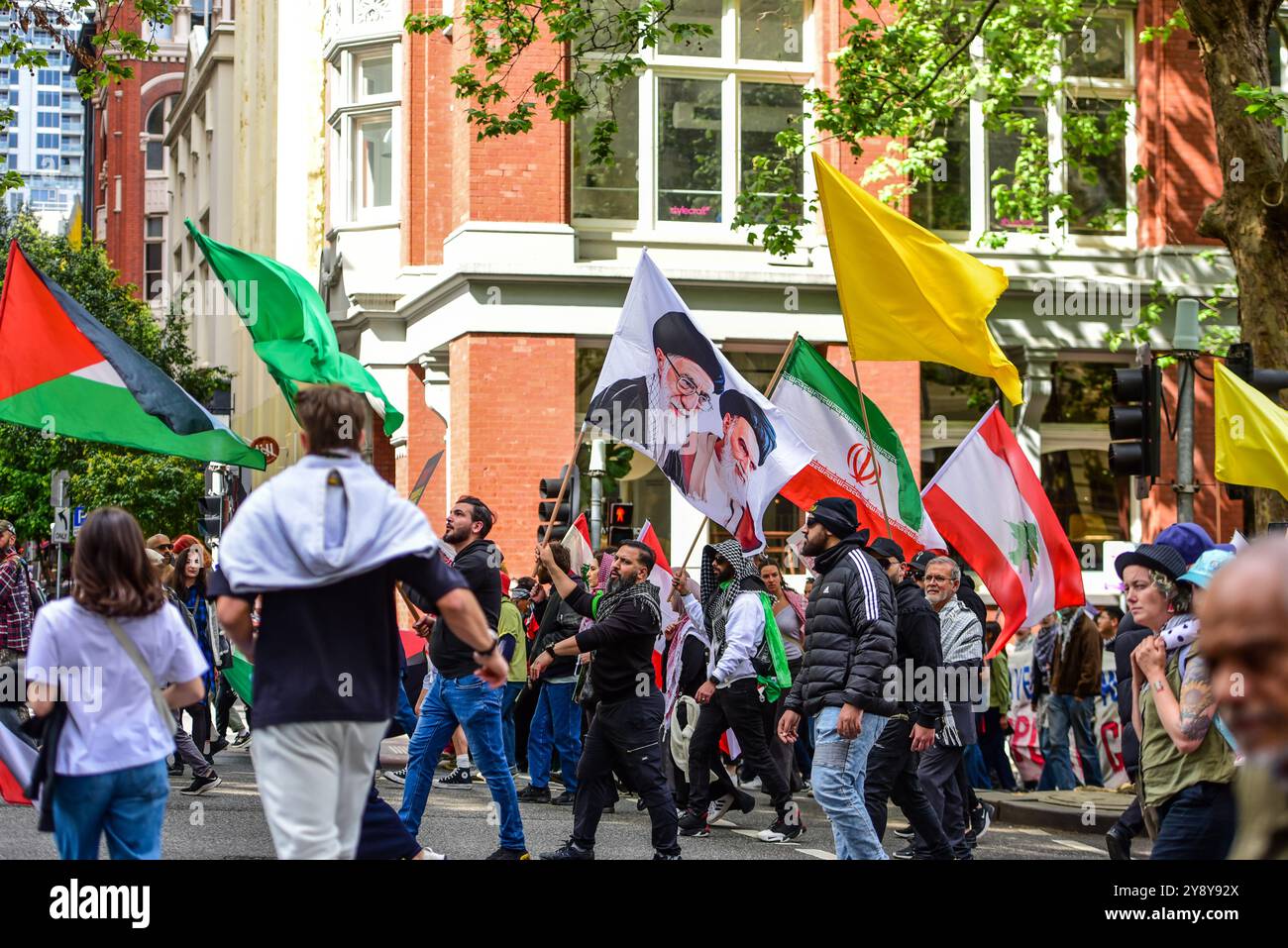 Melbourne, Australia. 6 ottobre 2024. Le persone ondeggiano le bandiere con i ritratti di Ali Khamenei e Ali al-Sistani durante l'ultima protesta filo-palestinese per le strade di Melbourne. I manifestanti pro-palestinesi a Melbourne marciano nel numero più alto finora con oltre 25000 persone che camminano dalla Victorian State Library al punto di riferimento più importante di Melbourne, la Flinders Station. Questo marzo ha commemorato un anniversario da quando l'ultima escalation tra Israele e Gaza è iniziata il 7 ottobre 2023. Credito: SOPA Images Limited/Alamy Live News Foto Stock