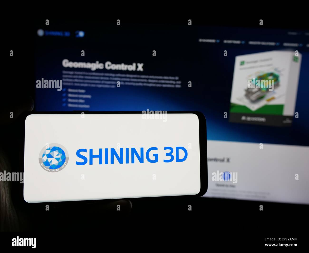 Persona che detiene un telefono cellulare con il logo della società cinese Hangzhou Shining 3D Co. Ltd. Sullo schermo di fronte alla pagina Web. Mettere a fuoco il display del telefono. Foto Stock