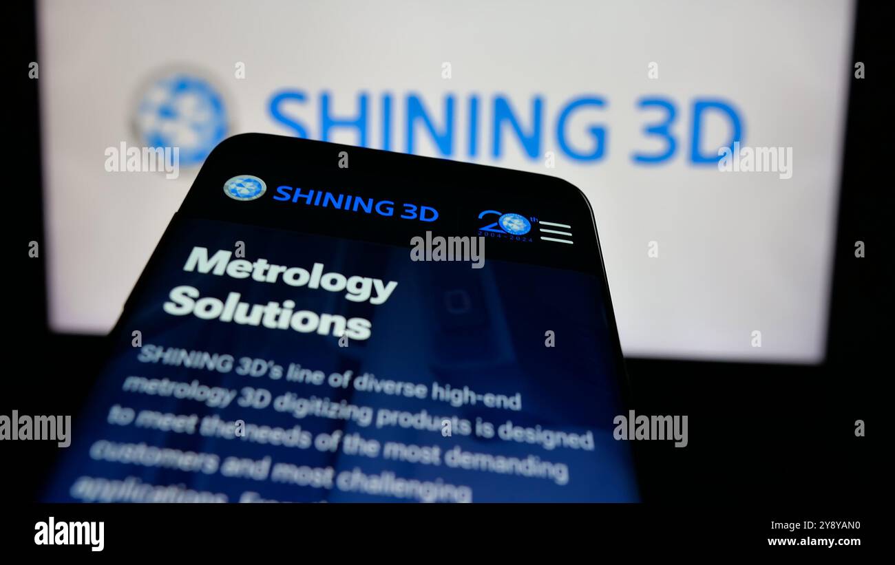 Telefono cellulare con sito Web della società cinese Hangzhou Shining 3D Co. Ltd. Sullo schermo di fronte al logo aziendale. Mettere a fuoco in alto a sinistra sul display del telefono. Foto Stock