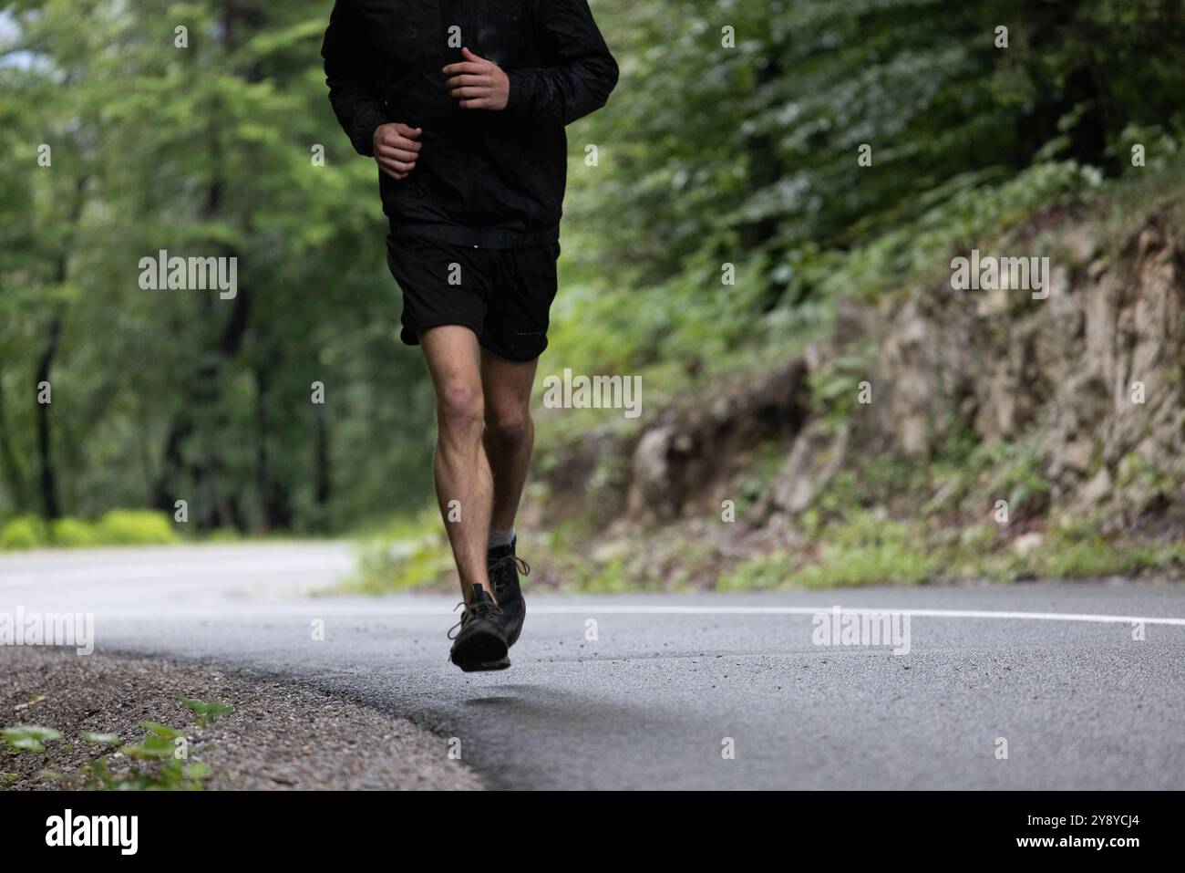 Corridore che corre su una strada asfaltata Foto Stock
