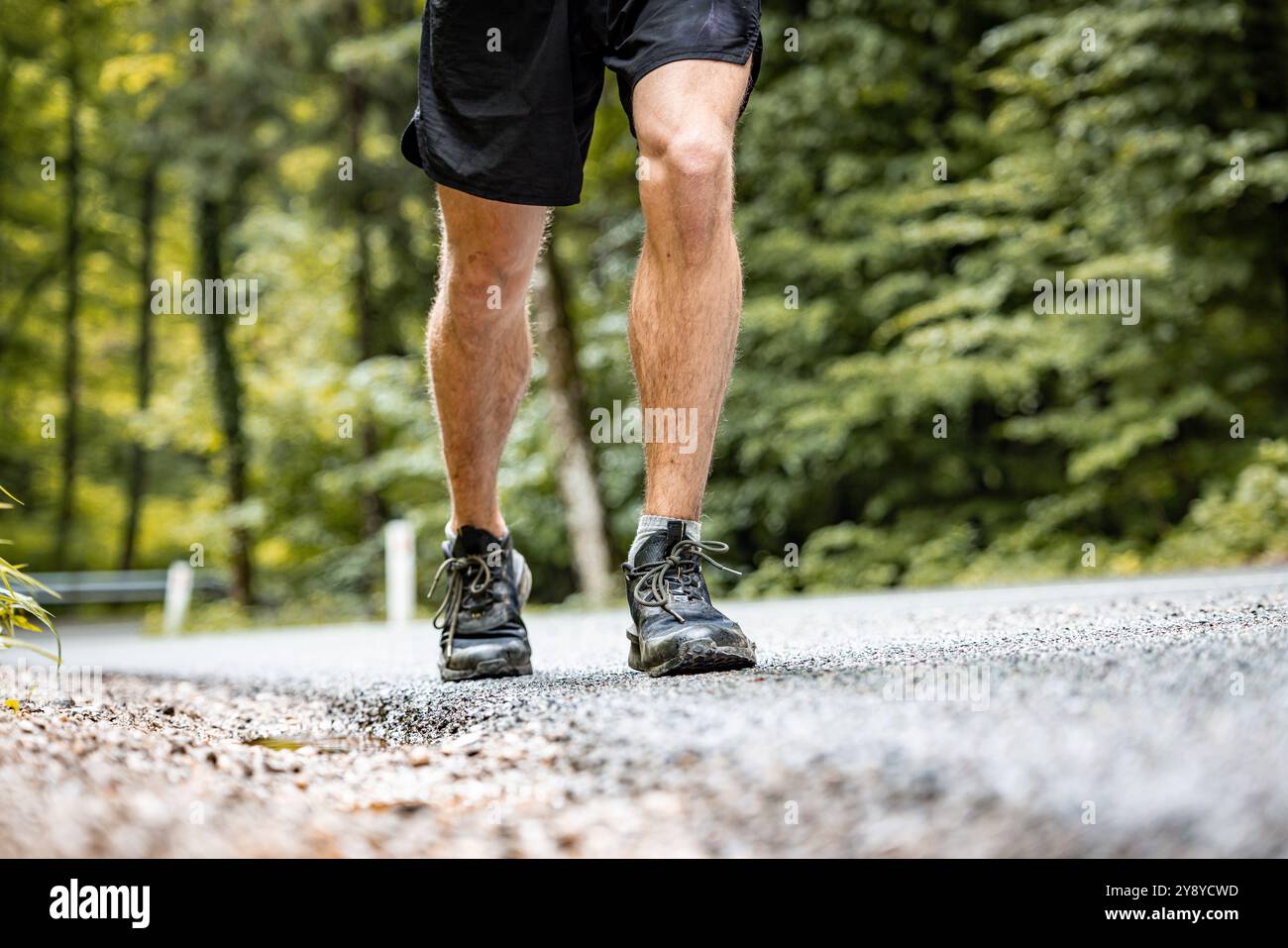 Atletica maschile non riconosciuta che corre su una strada asfaltata Foto Stock