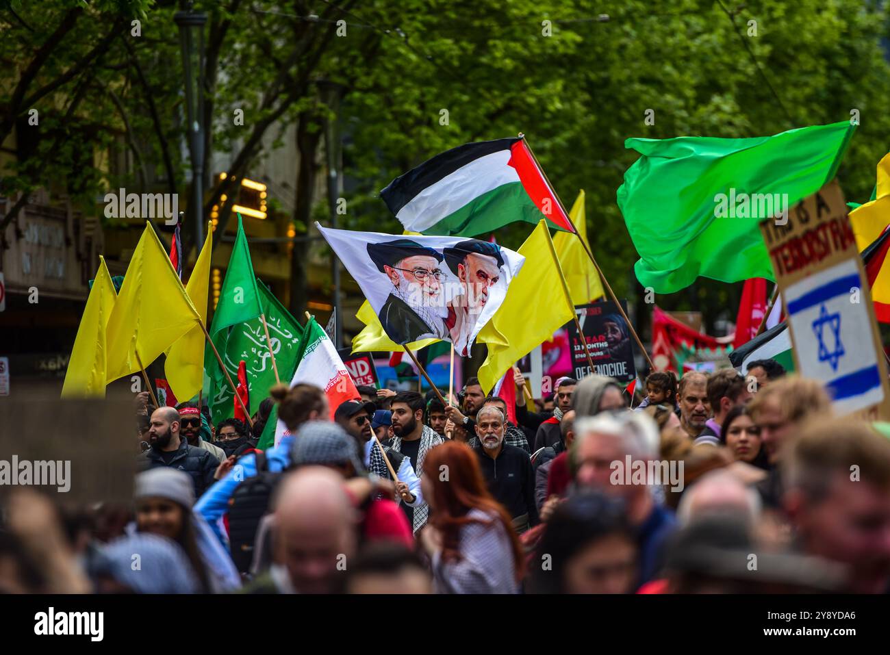 Una bandiera con Ali Khamenei e Ali al-Sistani insieme a bandiere gialle che sostituiscono le bandiere di Hezbollah sono viste durante l'ultima protesta pro-palestinese nelle strade di Melbourne. I manifestanti pro-palestinesi a Melbourne marciano nel numero più alto finora con oltre 25000 persone che camminano dalla Victorian State Library al punto di riferimento più importante di Melbourne, la Flinders Station. Questo marzo ha commemorato un anniversario da quando l'ultima escalation tra Israele e Gaza è iniziata il 7 ottobre 2023. (Foto di Alexander Bogatyrev/SOPA Images/Sipa USA) Foto Stock