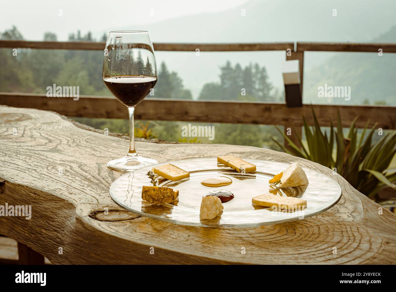 Un piatto di fette di formaggio con un bicchiere di vino rosso è sia la conclusione perfetta che l'inizio di un pasto tipico. Foto Stock