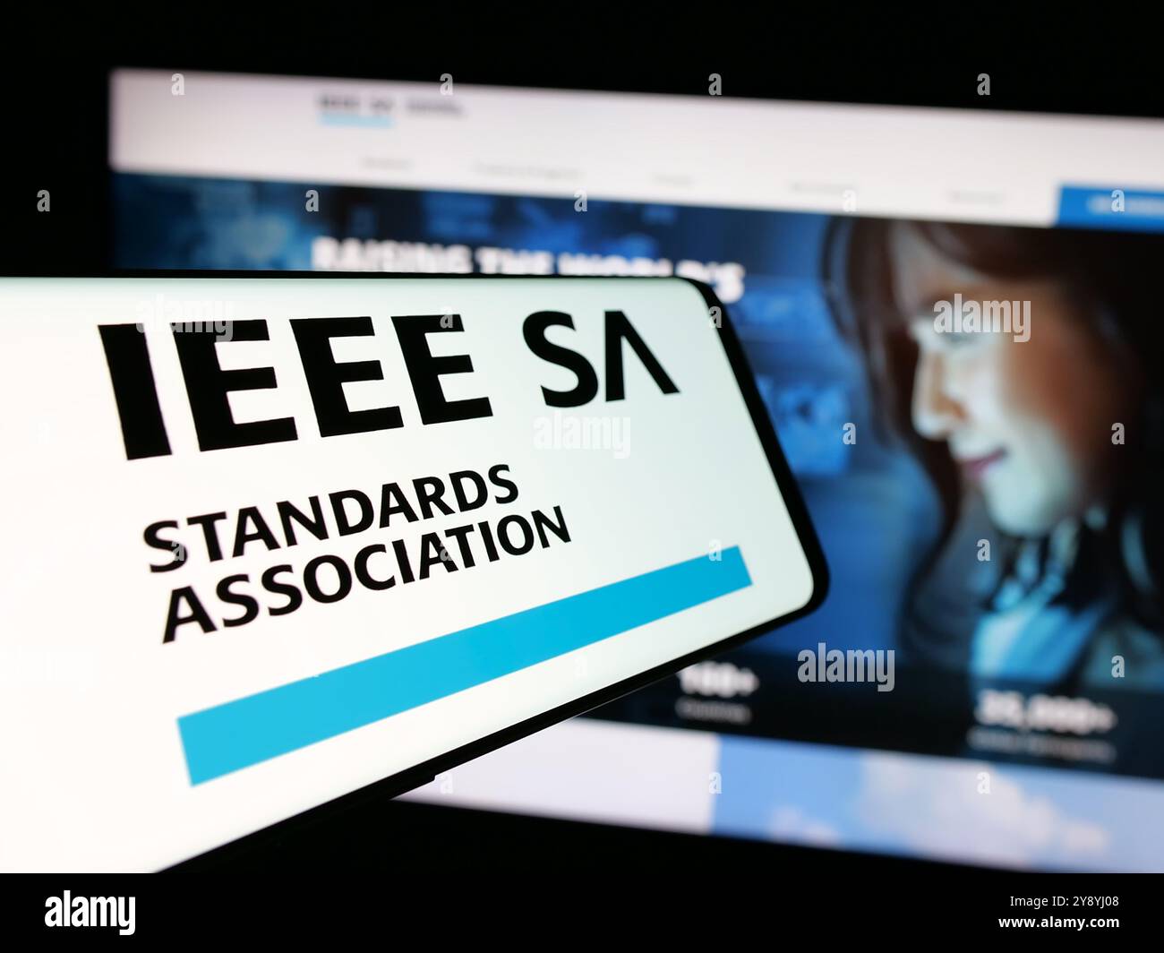 Smartphone con logo IEEE Standards Association sullo schermo davanti al sito Web. Messa a fuoco al centro del display del telefono. Foto Stock