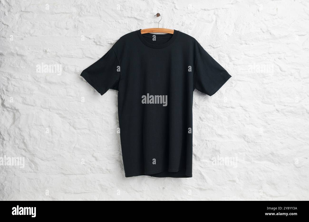Camicia nera appesa davanti al muro in pietra dipinta di bianco Foto Stock