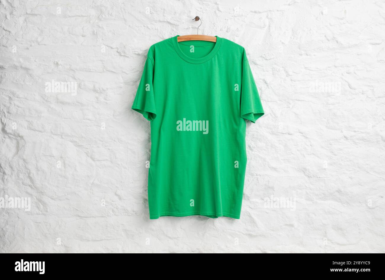 Camicia verde appesa davanti a un muro di pietra dipinta di bianco Foto Stock